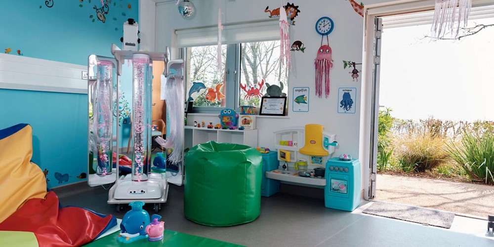 Image of sensory room with mats and children's toys, door open into gardens 