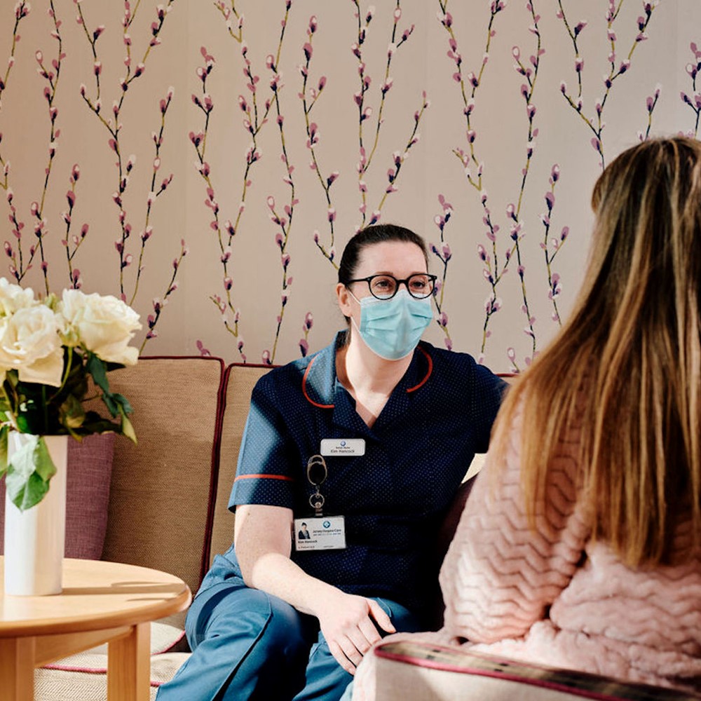 Image of nurse talking to patient in room with flowers on the table