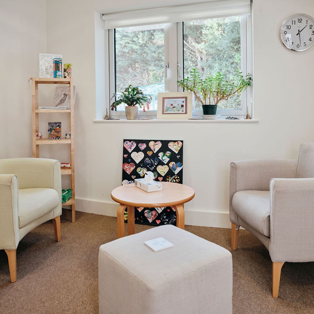 Image of bereavement counselling room, two chairs and a table with tissues on