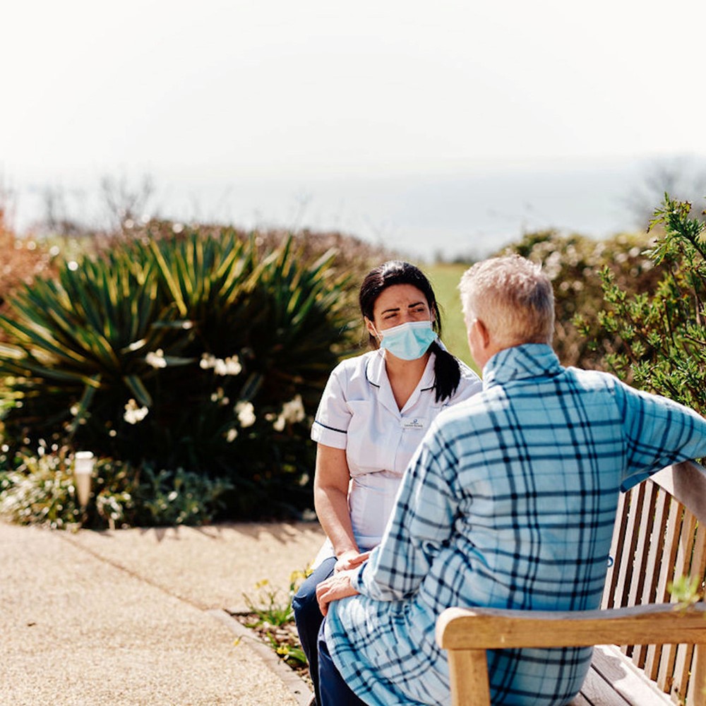 Image of nurse and patient sat on bench in Hospice Gardens
