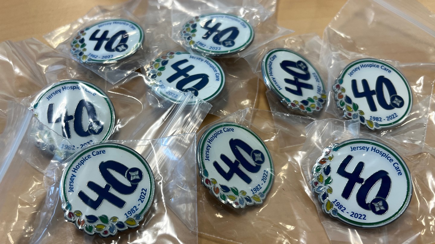 Selection of pin badges branded with Jersey Hospice Care 40th logo