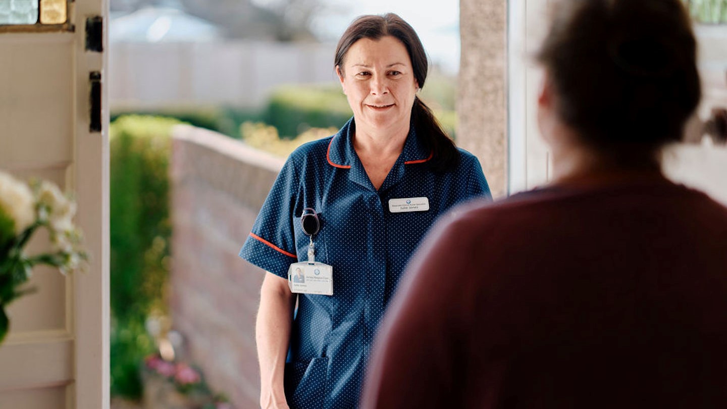 Image of community team nurse at doorway visiting a patient 