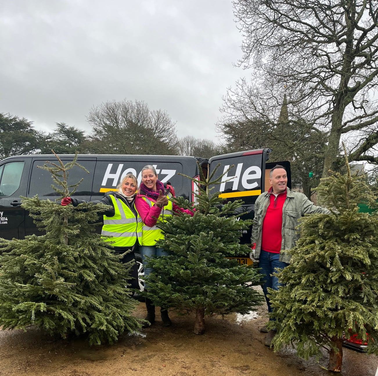 Image of three people with Christmas Trees