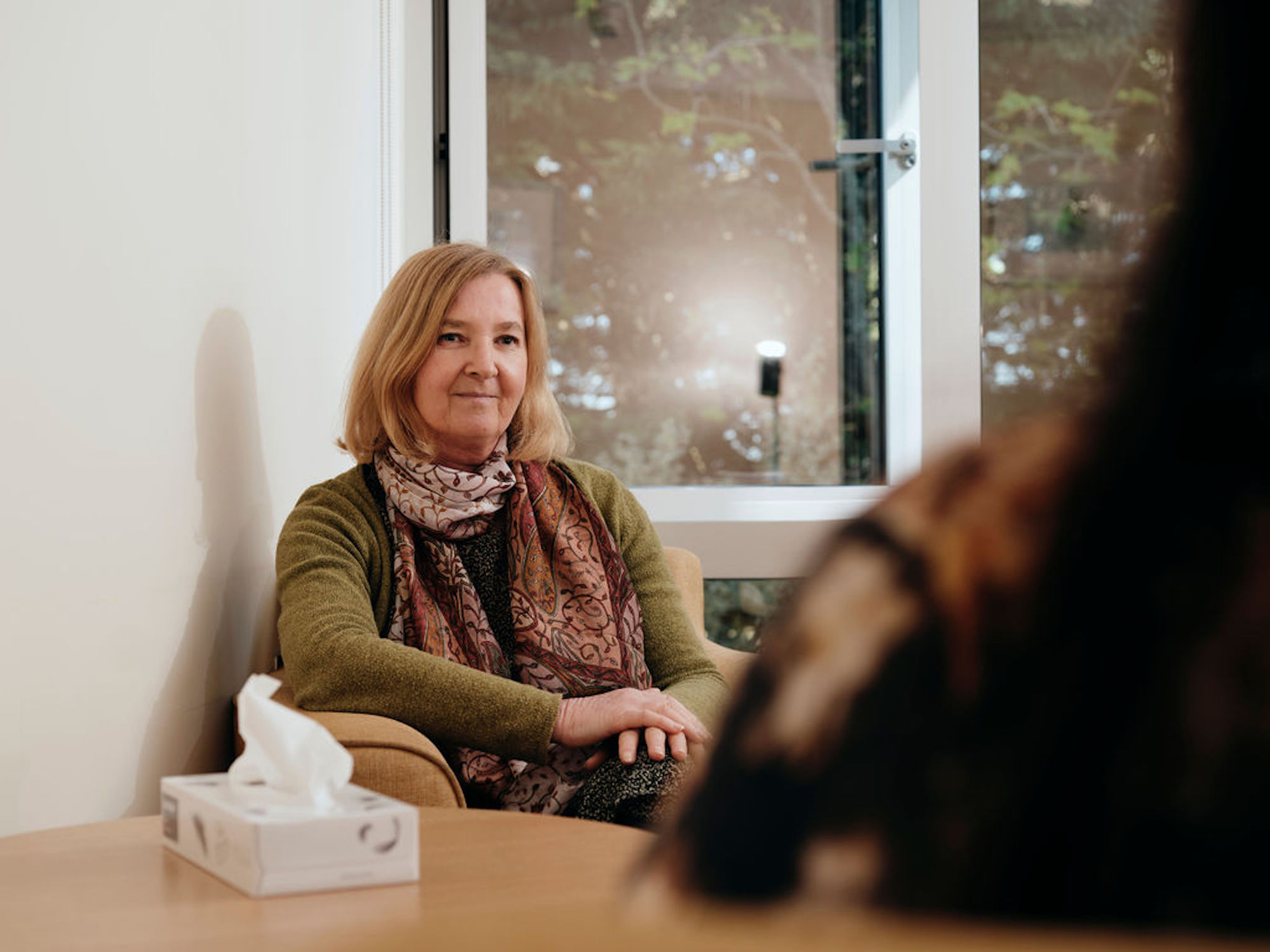 Image of bereavement counsellor talking to patient, box of tissues on table
